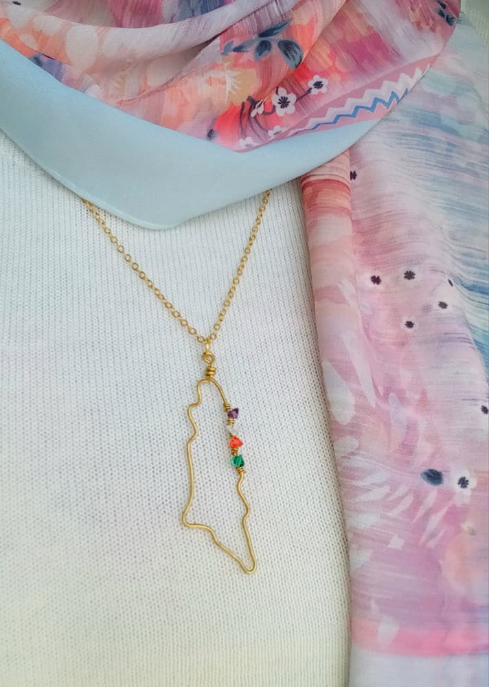 A copper chain in the shape of a map of Palestine with colorful flag beads