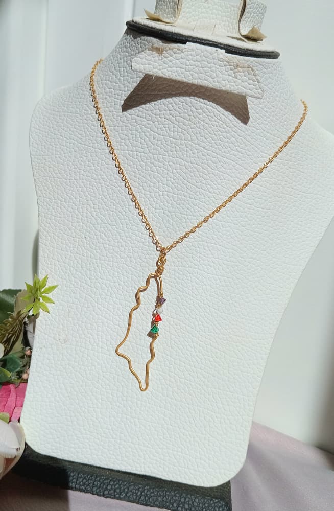 A copper chain in the shape of a map of Palestine with colorful flag beads